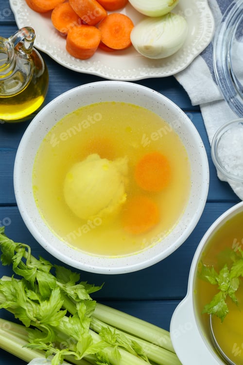 Preview: Delicious chicken bouillon and ingredients on blue wooden table, flat lay