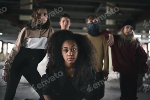 Preview: Group of teenagers gang standing indoors in abandoned building, bullying concept.
