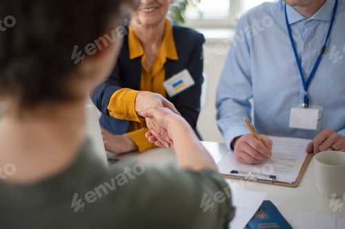 Preview: Woman and man volunteers helping Ukrainian woman to fill in forms at asylum centre.