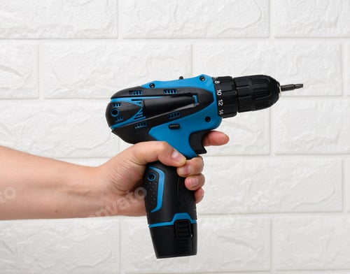 Preview: Hand in a textile glove holds a portable drill on a battery