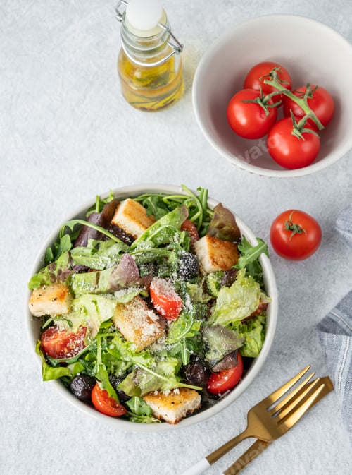 Preview: Salad with lettuce, tomatoes, croutons, olives and parmesan cheese in a bowl on a light background