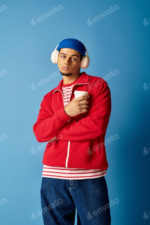 Preview: Trendy young man sipping coffee against a vibrant blue background
