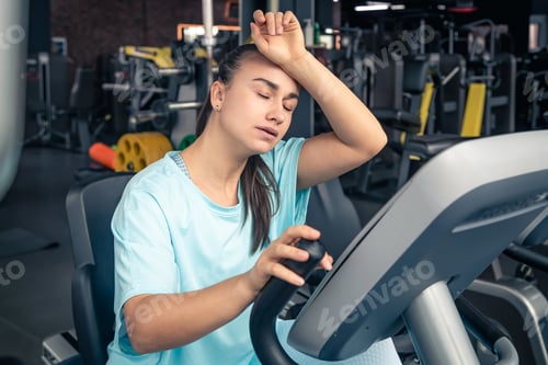 Preview: Fitness woman on bicycle doing cardio workout at gym.