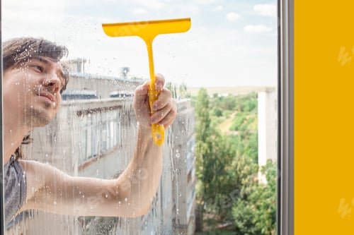 Preview: A man washes a window from the outside. The man sprays a blue cleaner