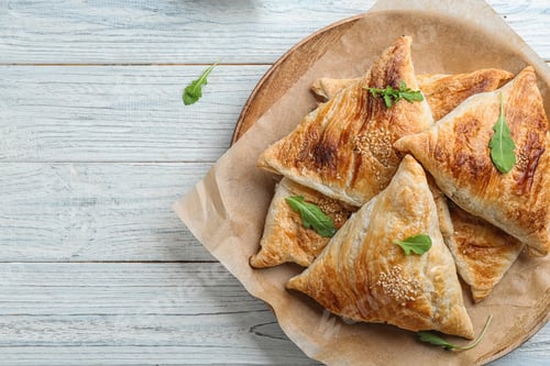 Preview: Fresh delicious puff pastry on white wooden table, top view. Space for text