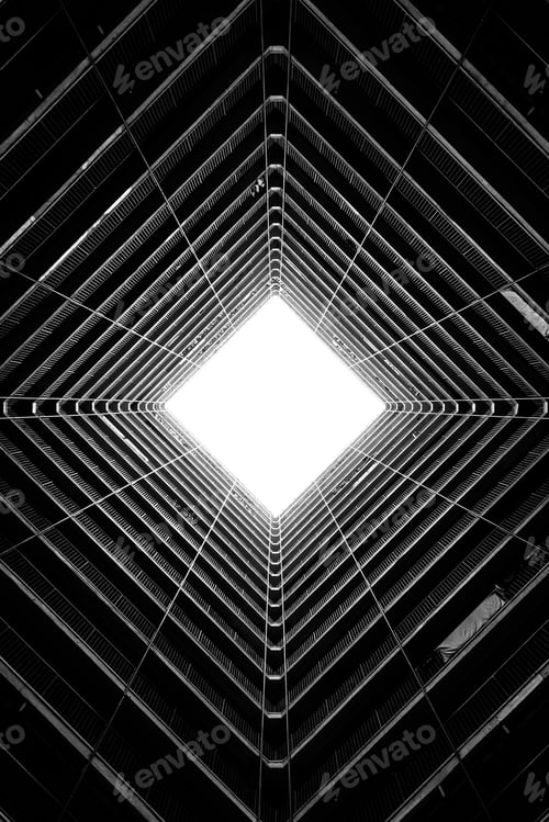 Preview: Vertical greyscale low angle shot of the light coming through the ceiling of a tall building