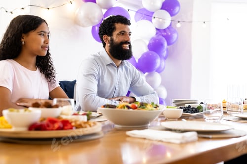 Preview: Family enjoying festive meal with colorful balloons and decorations in dining room