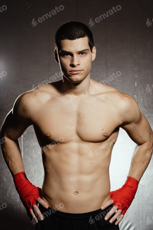 Preview: Athletic boxer getting ready before the fight over black background