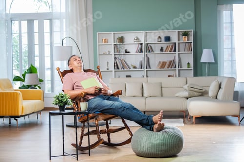 Preview: sian Indian handsome man with grey hair enjoy reading book at home or taking a nap