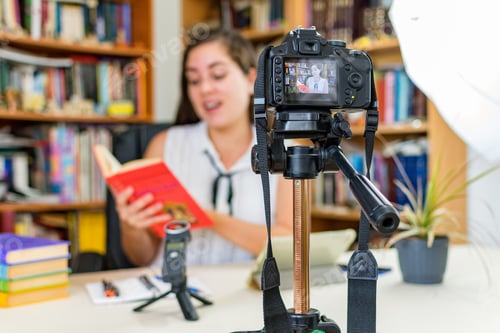 Preview: Camera on a tripod filming a vlogger at home sitting on his workspace