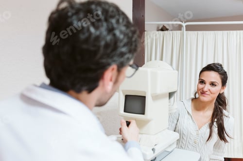 Preview: Ophthalmologist man examining young woman eyes in clinic. close up view