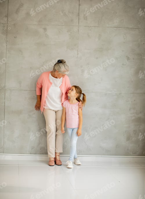 Preview: Little girl with her grandmother standing by the wall