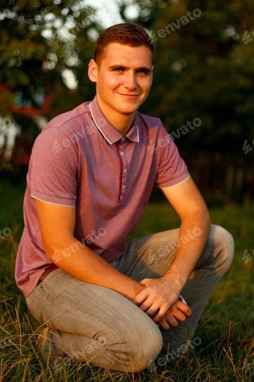 Preview: Happy people. Portrait of smiling young brunette man in purple polo shirt seating outdoor on nature
