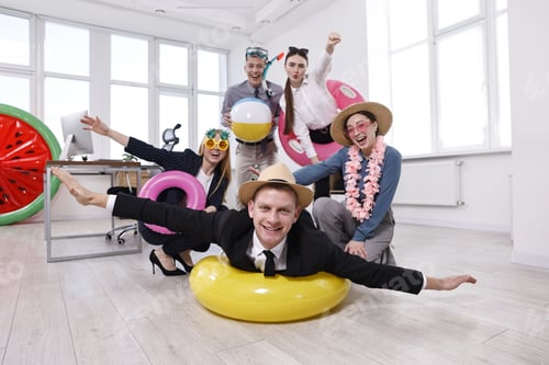 Preview: Happy coworkers with different beach accessories having fun in office, low angle view