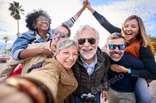 Preview: Group diverse funny mature tourist friends posing piggyback with hands joined in air taking selfie.