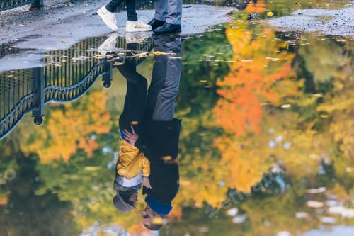 Aperçu: Young people in autumn park. Reflection in a puddle.