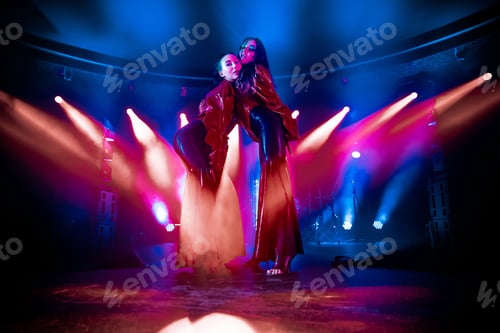 Preview: Close-up shot of two attractive women posing on a club stage with neon lights in the background