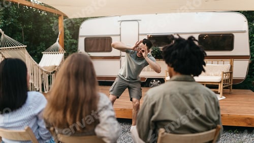 Preview: Multiracial young friends playing charades near motorhome during outdoor party