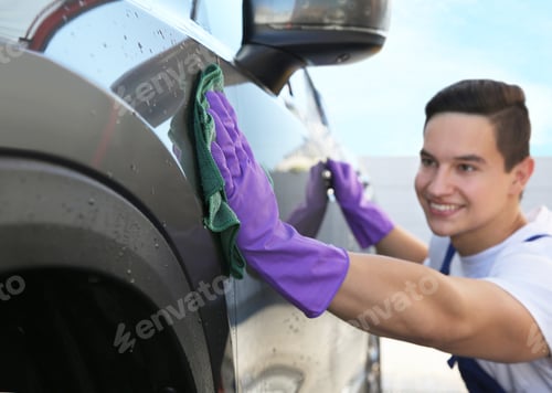 Preview: Male worker cleaning automobile with rag at car wash