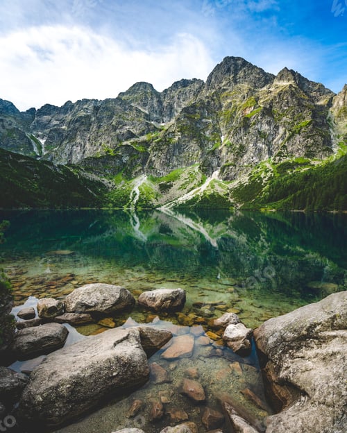 Preview: Vertical closeup of Morskie Oko(Eye of the Sea) lake with stones on the bank, blue sky background