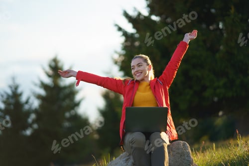 Preview: Happy young woman using laptop in summer nature, outdoor office concept