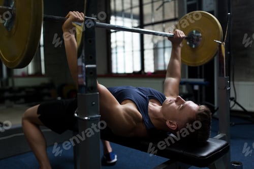 Preview: young man flexing muscles with barbell in gym