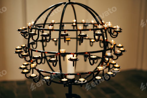 Preview: Votive candles stand on a ball-shaped stand in a church