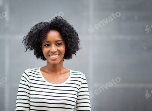 Preview: Portrait of attractive young african american woman by gray wall