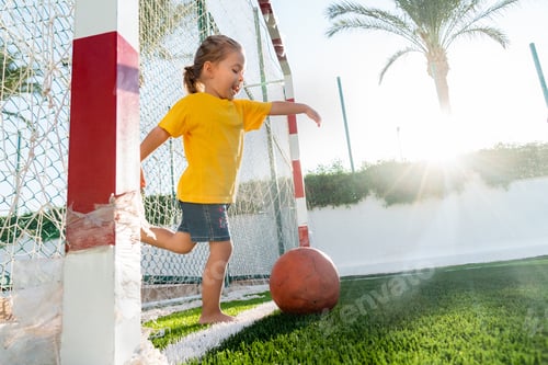 Preview: Cute little girl kicking soccer ball while standing in gateway
