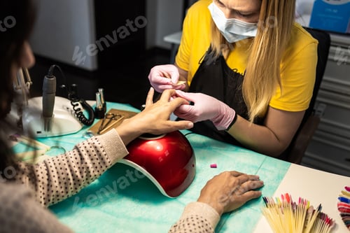 Preview: the master of manicure and pedicure removes gel polish from the nail. close-up manicure. nail extens