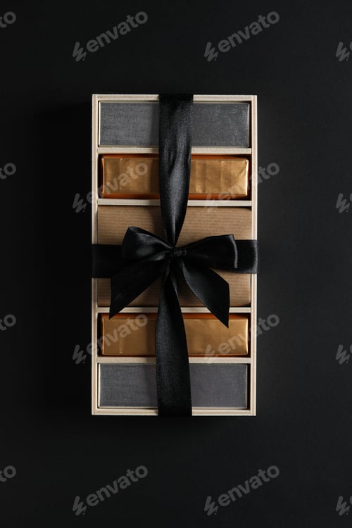 Preview: Chocolates in box with ribbon on black background, top view
