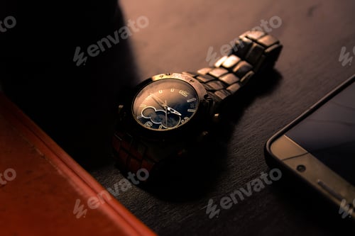 Preview: Old metallic wristwatch and broken screen mobile phone in dark moody light