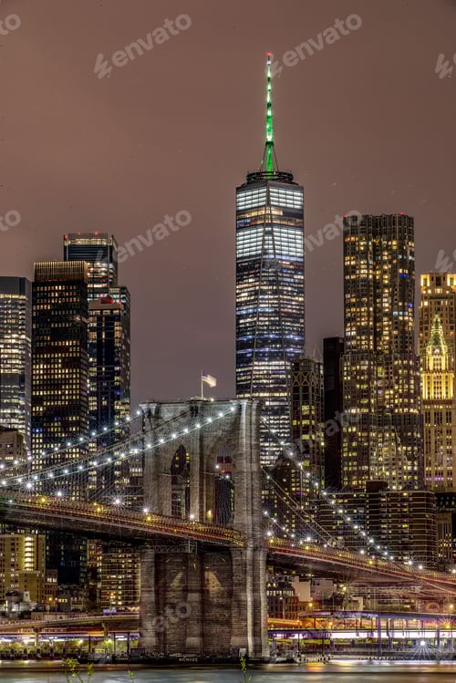 Preview: Brooklyn Bridge illuminated with lights at night on the background of the modern cityscape