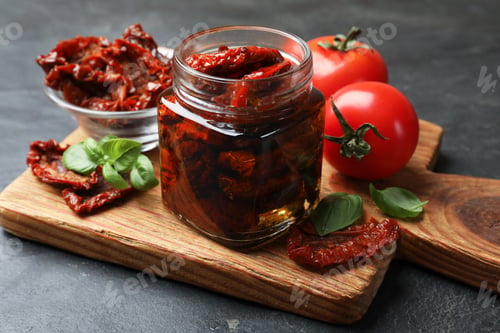 Preview: Tasty sun dried tomatoes and fresh vegetables on black table, closeup