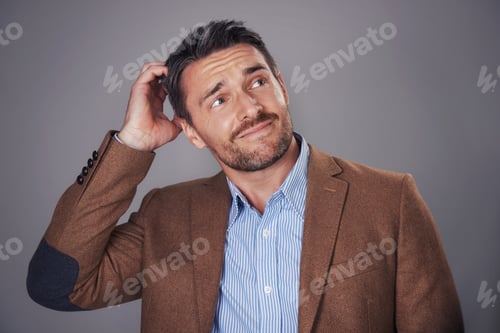 Preview: Studio shot of a man scratching his head against a gray background
