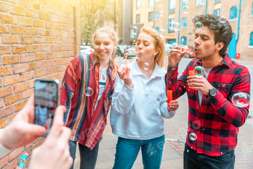 Preview: Happy friends playing with soap bubbles together