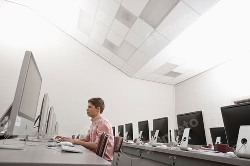 Preview: A school room, a computer lab with rows of screens, one teenager working