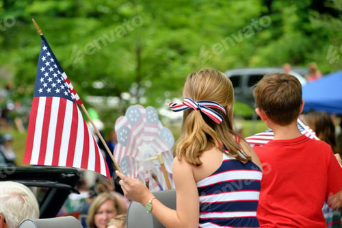 Preview: boy and girl in patriotic clothes waving flags in the local Independence Day July 4th parade