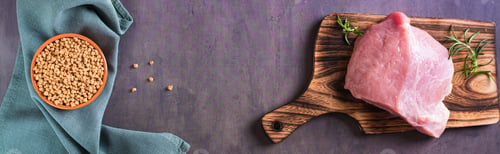 Preview: A piece of fresh meat on a cutting board and soy mince in a bowl top view web banner