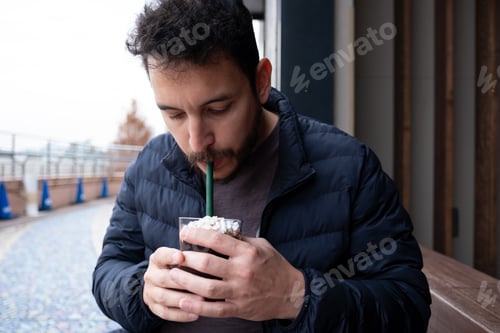 Preview: Man drinking a cold beverage with whipped cream outside in Odaiba