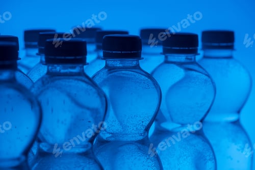 Preview: close up of plastic water bottles in rows on neon blue background