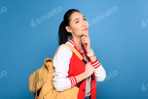 Preview: side view of pensive asian student with backpack isolated on blue