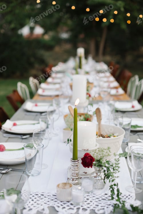 Preview: Long table set with plates and glasses, food and drink in a garden.