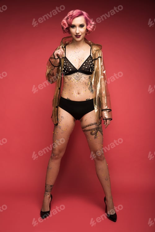 Preview: beautiful pink haired girl with tattoos in lingerie and raincoat infront of red background