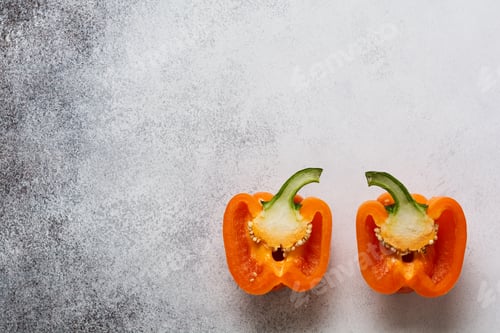 Preview: Two orange fresh peppers cut in half on a gray concrete old background. Cooking concept. Top view