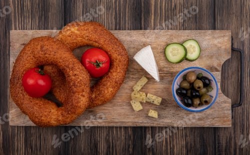 Preview: top view of turkish bagels on a wooden kitchen board with olives on a bowl with chopped slices of