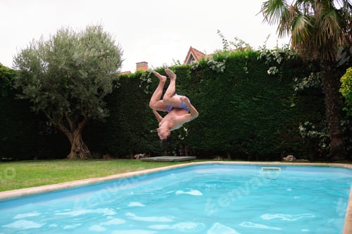 Preview: Young caucasian man jumping into the swimming pool.