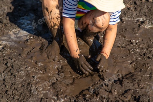 Preview: Child playing in mud. Selective focus.