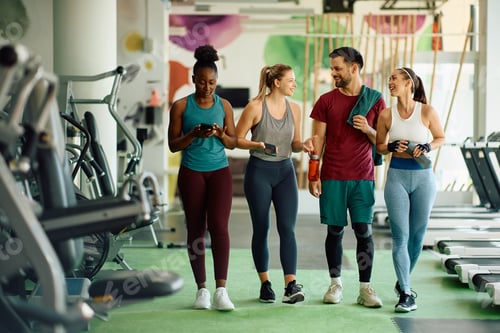 Preview: Happy athletic friends communicating after sports training in a gym.