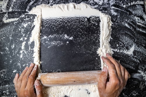 Preview: Female hands keep rolling pin with flour on dark table. Baking background. Flour, cooking and bake